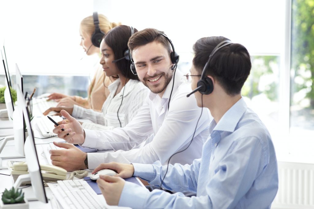 Happy male technical support operators having friendly chat at call centre