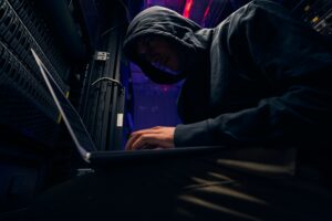 Expert cybercriminal installing malware using his laptop