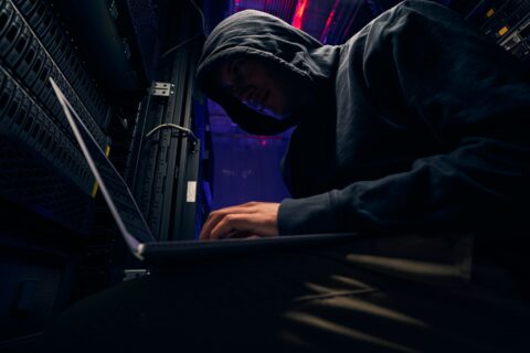 Expert cybercriminal installing malware using his laptop